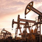 Oil pump jacks at sunset sky background. Toned.